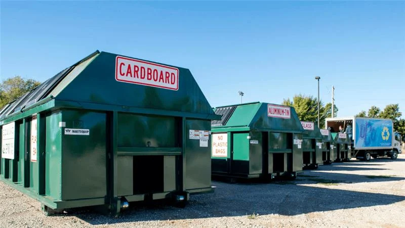 Recycling station with labeled bins for cardboard, aluminum, glass, and paper to support packaging sustainability.