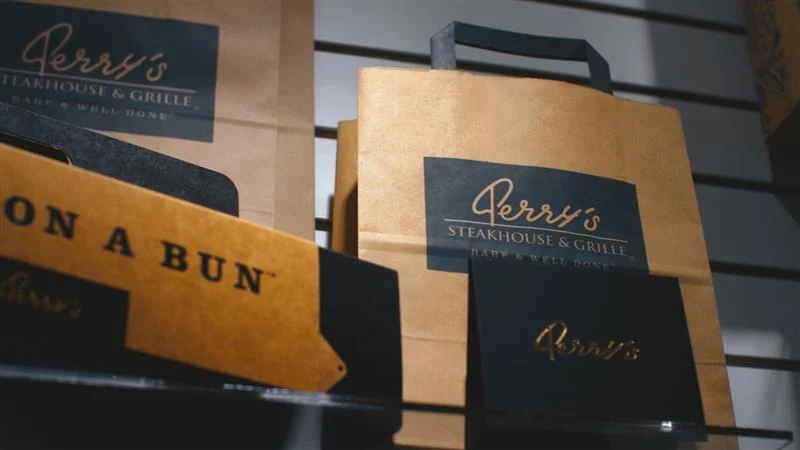 Branded paper to-go bags showcasing custom print and structural design for retail packaging.
