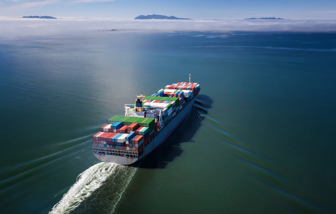 A cargo ship carries containers, representing supply chain planning needed for California’s Plastic Bag Ban transition.