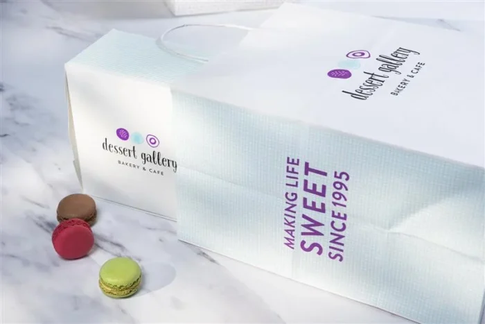 Dessert Gallery Bakery & Café packaging set with branded boxes and paper bags against a pink background.