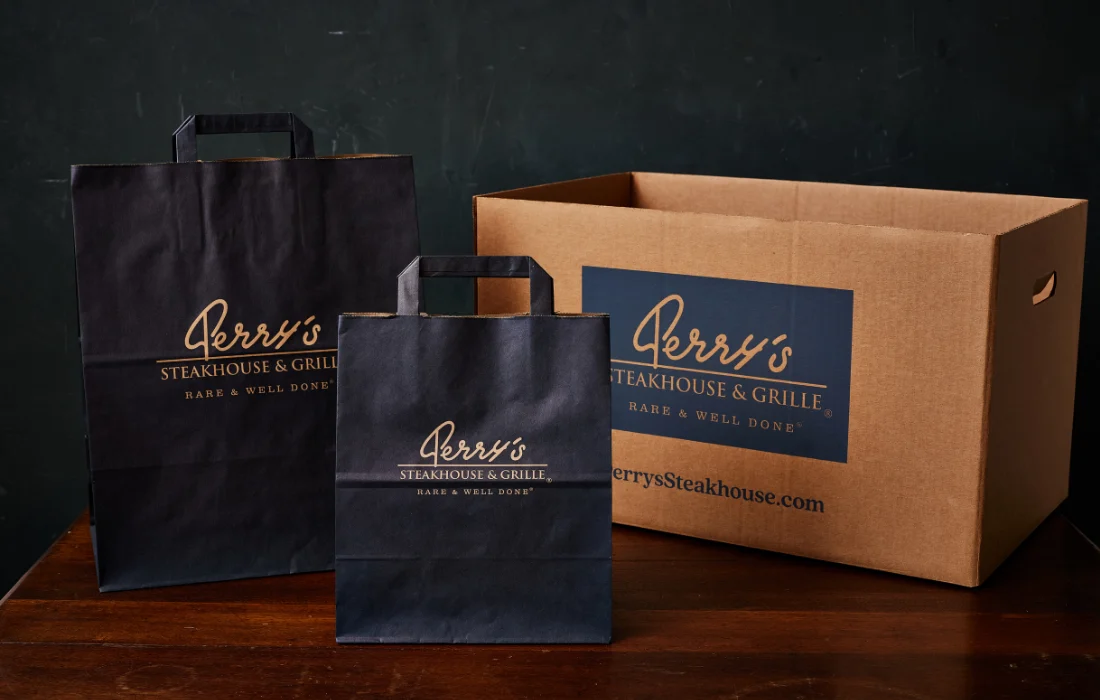 Custom “Bites on a Bun” branded catering box with handle from Perry’s Steakhouse.
