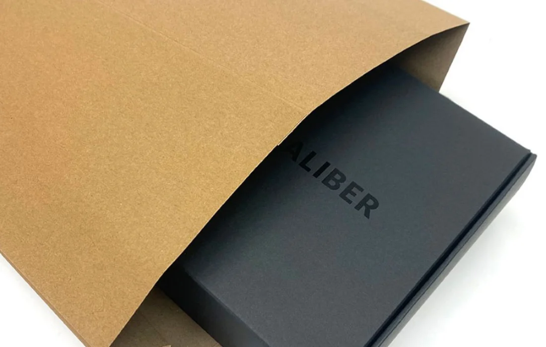 Kraft paper mailer partially open with black box inside, highlighting sleek ecommerce packaging presentation.