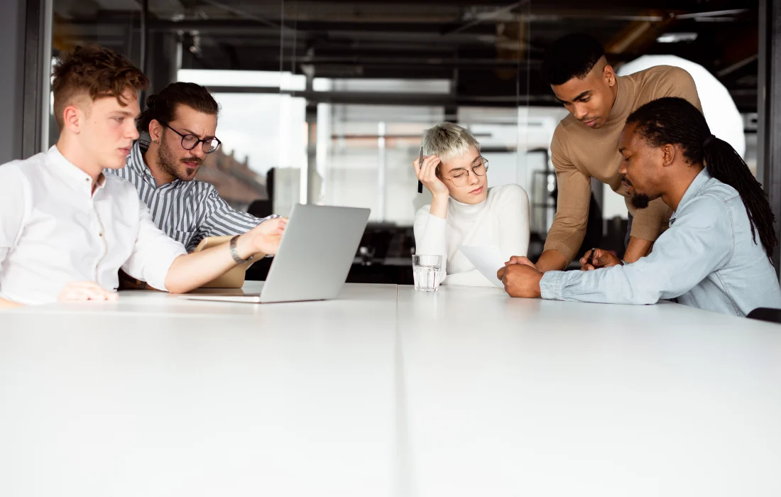 Diverse professionals discuss strategies on a laptop, potentially planning how to reduce packaging waste.
