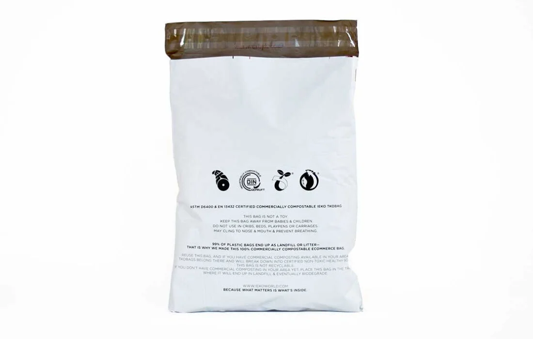 A white commercially compostable shipping mailers with black text and symbols, promoting a sustainable alternative to plastic.