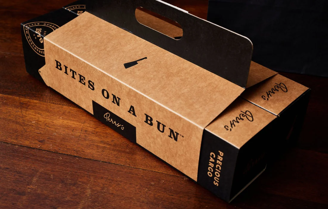 Eco-friendly takeout box with handle featuring bold black typography “Bites on a Bun” and minimalist restaurant branding.