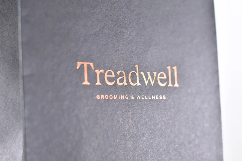 Custom packaging design showing a dark textured bag with copper Treadwell logo, communicating grooming and sophistication.