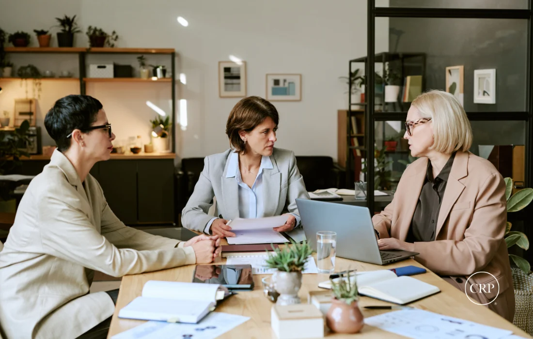Three women reviewing packaging procurement documentation and supplier diversity reports.